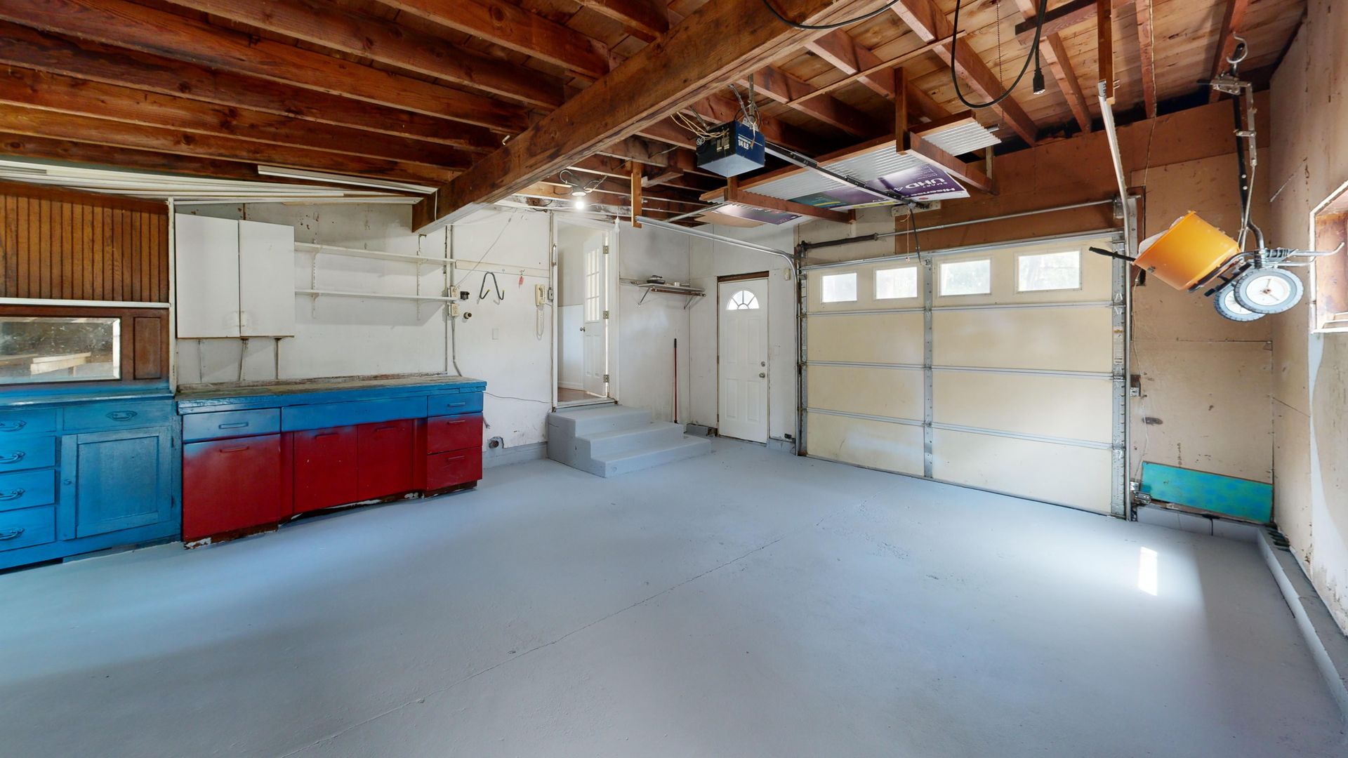 Empty garage with open space and colorful storage cabinets.